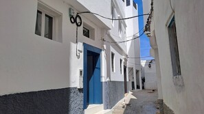 A narrow street with white buildings, a blue door, and a cat lying on the ground. - Charming 19th-century House With Sea Views in Tangier (Tangier)