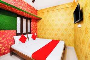 A room with a bed, a window, a TV, and patterned walls. - Hotel Sri Jagannath Near Sea Beach  (Puri)
