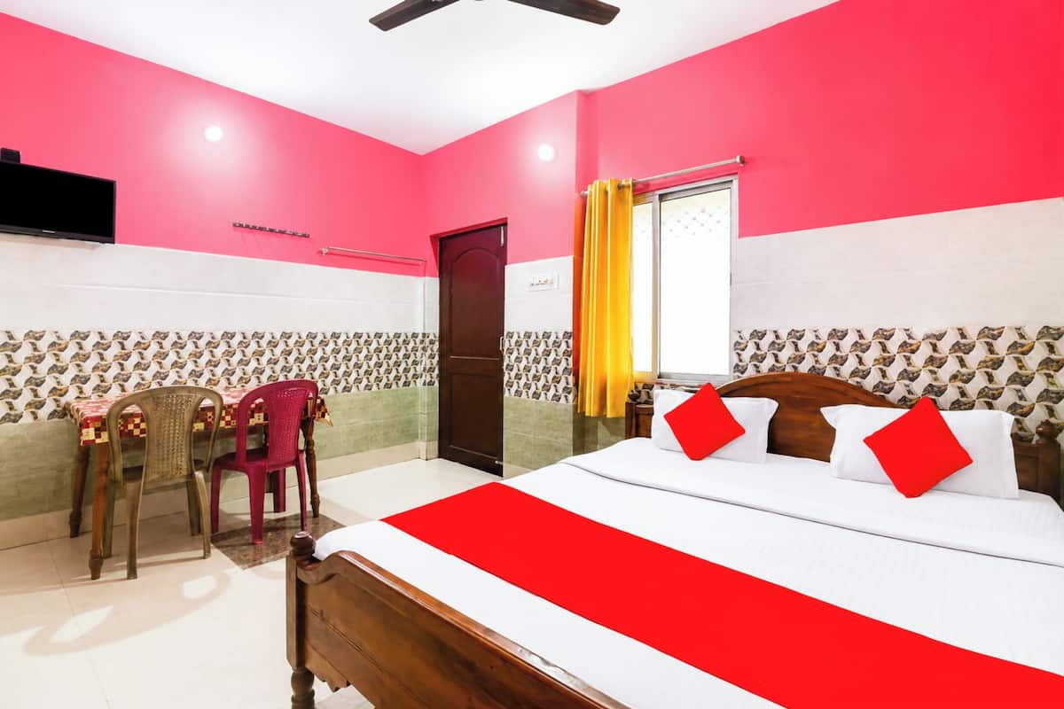 A hotel room with a bed, a desk with a chair, a television, and a window with curtains.