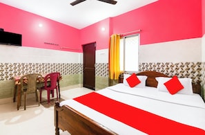 A hotel room with a bed, a desk with a chair, a television, and a window with curtains. - Hotel Sri Jagannath Near Sea Beach  (Puri)