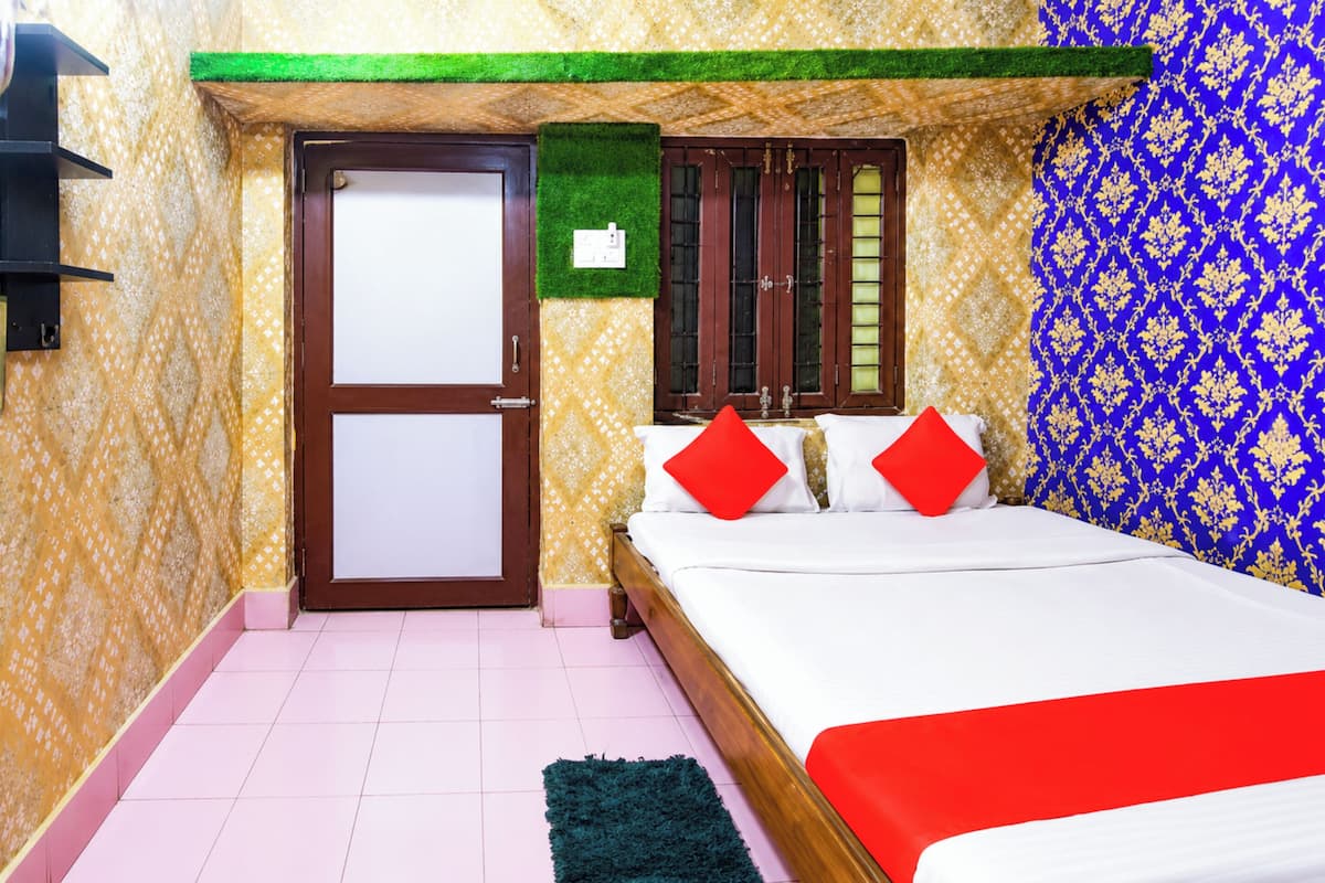 A bedroom with a bed, a door, and patterned wallpaper.