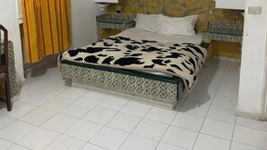 A bedroom with a bed, a ceiling fan, a window with curtains, and a tiled floor. - Hôtel Russie (Tunis)