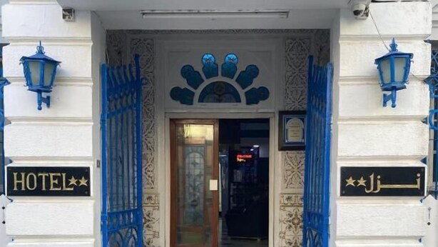 A hotel entrance with a blue gate, a sign reading 'HOTEL,' and a decorative archway. - Hôtel Russie (Tunis)