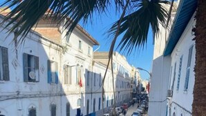 A street view with buildings, parked cars, and pedestrians. - Hôtel Russie (Tunis)