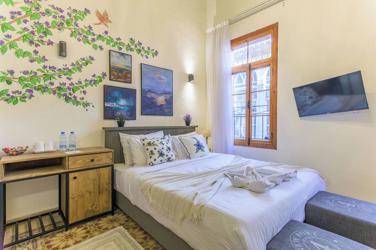 Un dormitorio con cama, mesita de noche, escritorio, ventana y decoración en la pared.