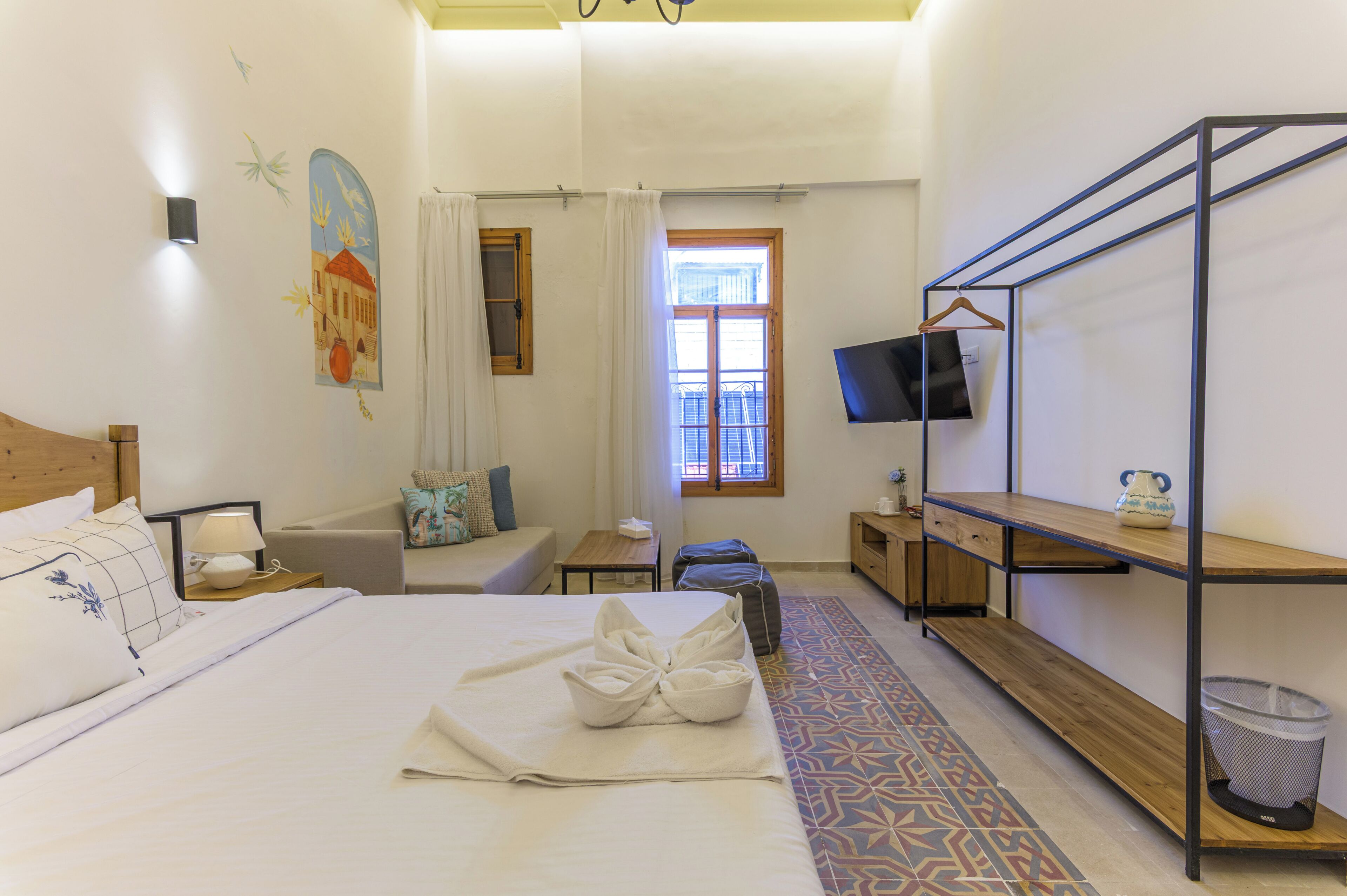 Une chambre d’hôtel équipée d’un lit, d’une télévision, d’un bureau, d’une chaise, d’une fenêtre et d’une étagère fixée au mur.