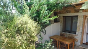 Une terrasse avec un mur en pierre, une table en bois et des chaises.