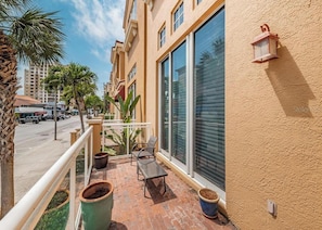 Ein Balkon mit Stuhl, Topfpflanzen und einem großen Fenster.