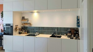 Een moderne keuken met witte kasten, een zwart aanrecht, een spoelbak en een koffieapparaat.
