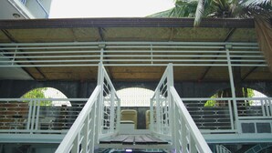 A white metal bridge with railings, leading to a covered area with a thatched roof and arched windows. - Healing Hotel (Angeles City)