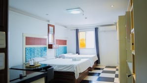 A hotel room with two beds, a desk, a mirror, and a window with curtains. - Healing Hotel (Angeles City)