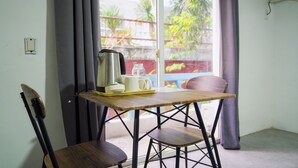 A room with a wooden table, two chairs, a kettle, and a tray with cups and bottles. - Healing Hotel (Angeles City)