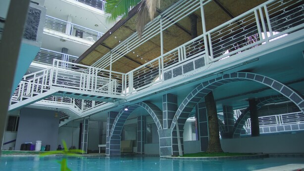 A multi-level swimming pool with glass railings and a thatched roof. - Healing Hotel (Angeles City)