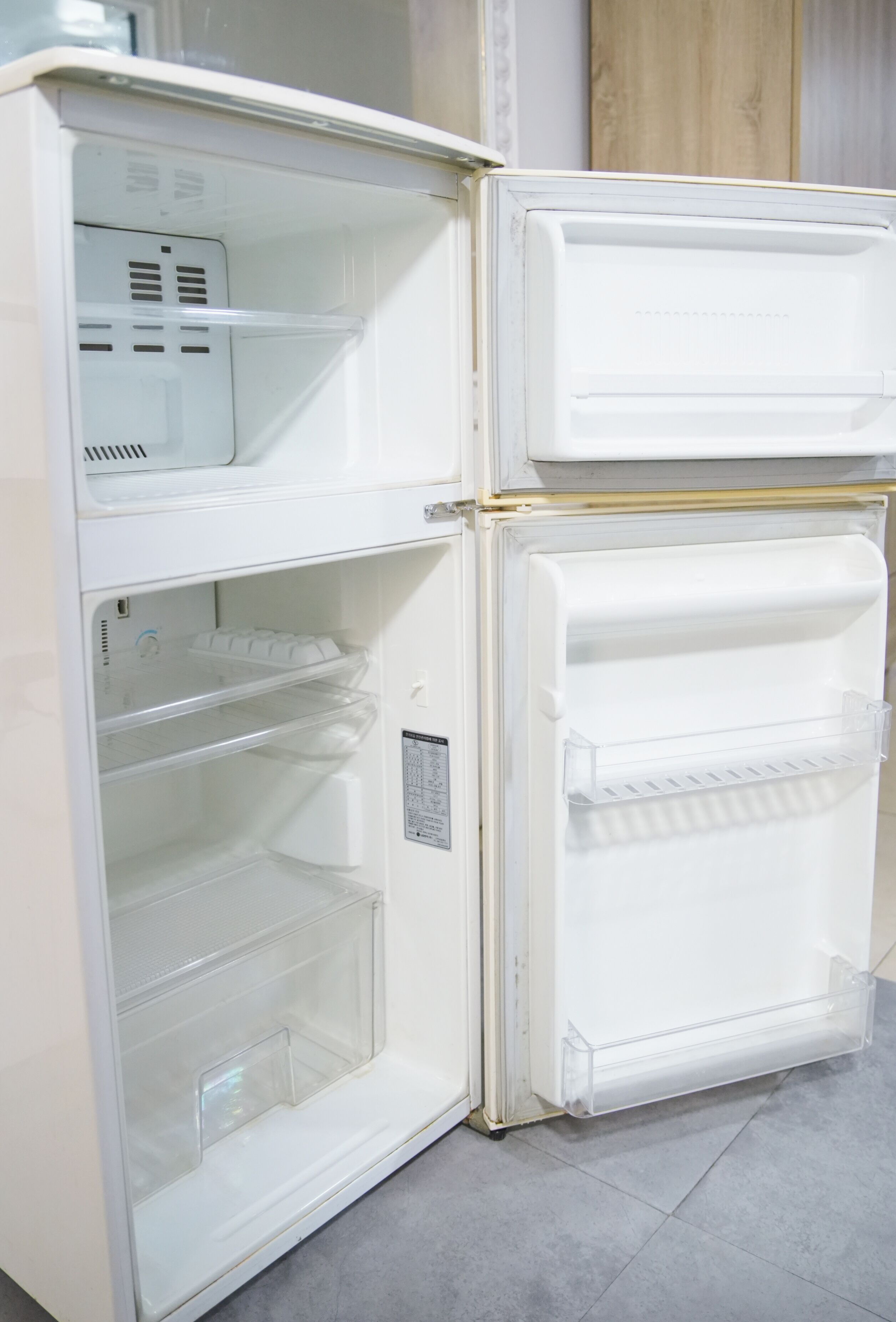 Uma geladeira branca com duas portas, compartimento para congelador e dispensador de água.