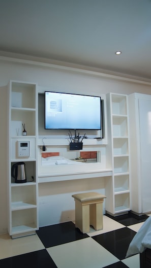 Una sala moderna con un televisor de pantalla plana montado en una pared blanca, un taburete de madera y un suelo a cuadros blanco y negro.