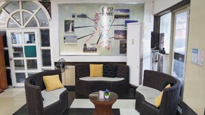A lobby with wicker furniture, a central coffee table, and a wall with a map and photos. - Healing Hotel (Angeles City)