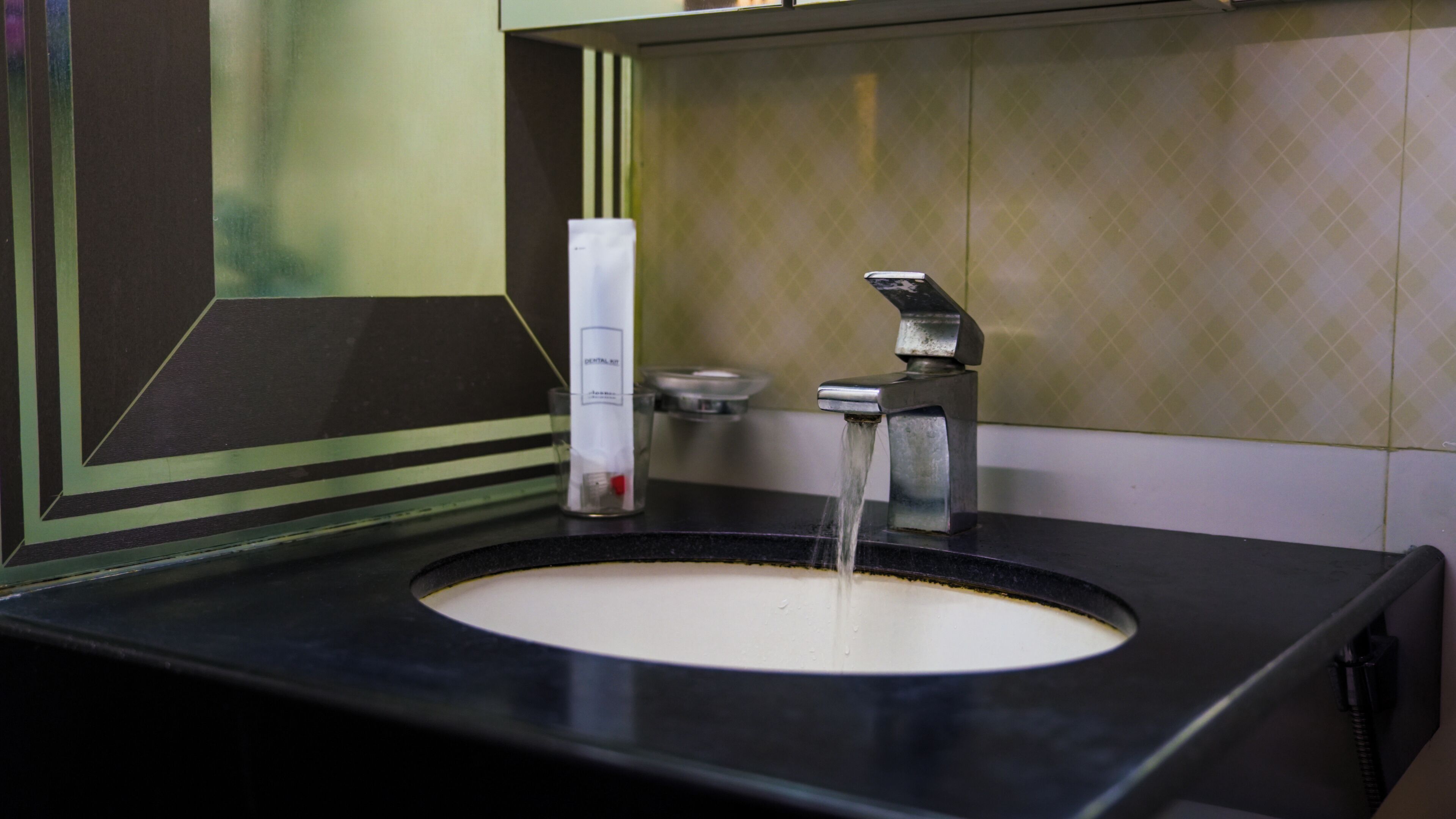 A bathroom sink with a faucet, a soap dispenser, and a mirror.