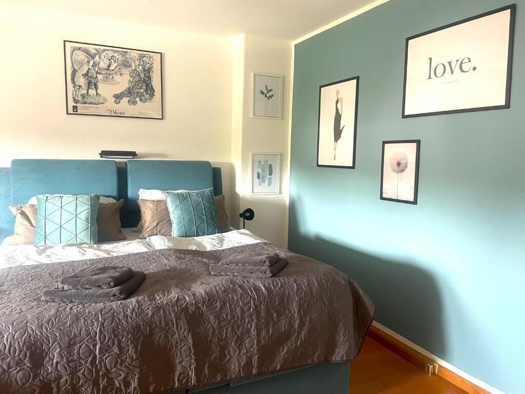 A bedroom with a bed, pillows, a headboard, and wall art.