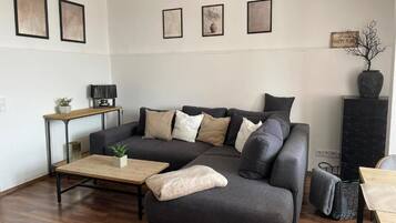 Ein modernes Wohnzimmer mit einem Ecksofa, einem Couchtisch, einem Beistelltisch mit Lampe und einer dekorativen Vase.