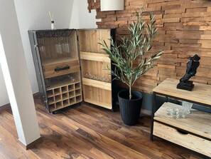 A corner with a wooden cabinet with multiple shelves, a potted plant, and a small table with a sculpture. - Neuseenland Apartment, between the most beautiful lakes of Leipzig's Neuseenland (Rötha)