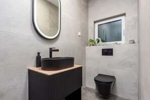 A modern bathroom with a round mirror, a black sink, a window, and a black toilet. - Villa Salt2 Zadarvillas (Nin)