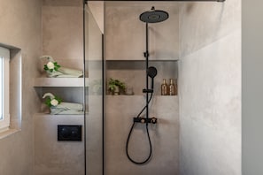 A modern shower with a handheld showerhead, a control panel, and a shelf with toiletries. - Villa Salt2 Zadarvillas (Nin)