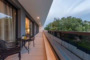 A balcony with a glass railing, a table with chairs, and a view of trees. - Villa Salt2 Zadarvillas (Nin)