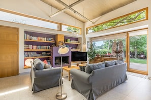 Ein geräumiges Wohnzimmer mit einer Sofagarnitur, einem Kamin, Bücherregalen und einem Fernseher.