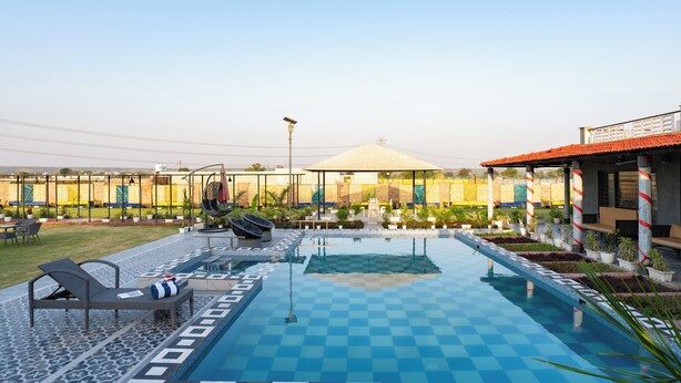 A swimming pool with checkered tiles, lounge chairs, and potted plants. - Alaya Stays Batlaw Classic 5 BHK Villa with Pvt Pool & Gazebo (Gurugram)