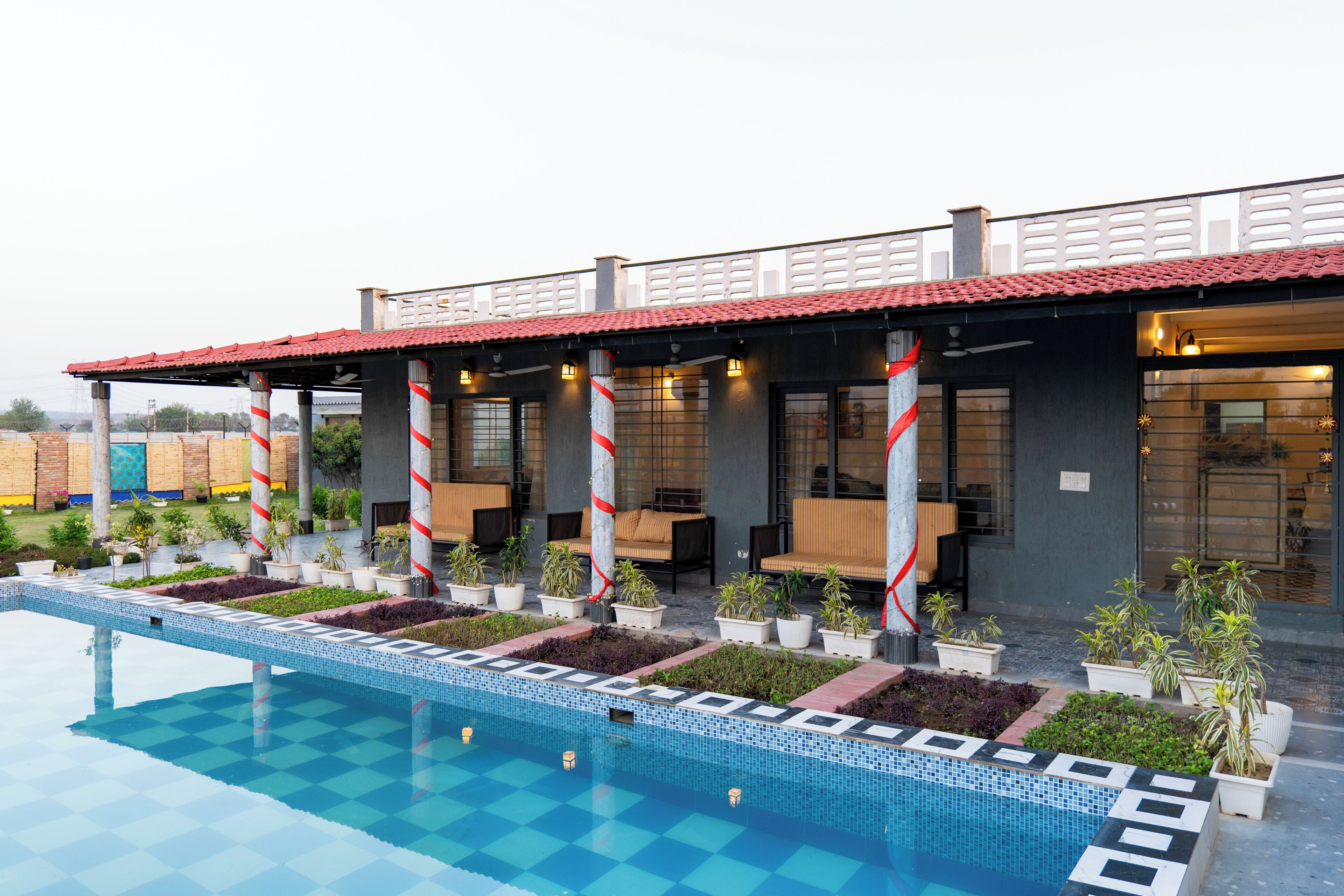 A hotel with a swimming pool, outdoor seating, and potted plants.