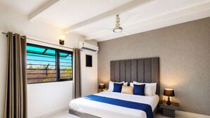 A hotel room with a bed, curtains, a ceiling fan, a window with a view, and a wall-mounted air conditioner. - Alaya Stays Batlaw Classic 5 BHK Villa with Pvt Pool & Gazebo (Gurugram)