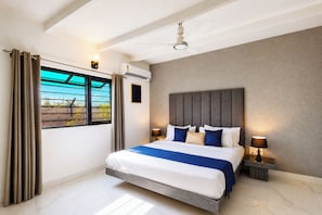 A hotel room with a bed, curtains, a ceiling fan, a window with a view, and a wall-mounted air conditioner.
