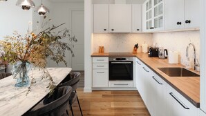 A modern kitchen with white cabinets, a wooden countertop, a built-in oven, and pendant lights. - Sea View Apartment in Luštica Bay (Radovići)