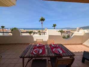 Eine Terrasse mit Tisch für zwei Personen, mit Blick auf die Küste.