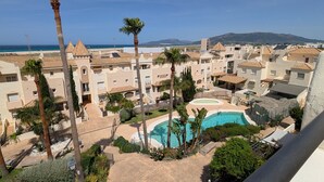 Una zona residenziale con piscina, palme e edifici dall'architettura mediterranea.