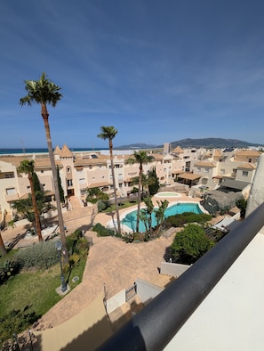 Ein Wohngebiet mit Swimmingpool, Palmen und Gebäuden im mediterranen Stil.