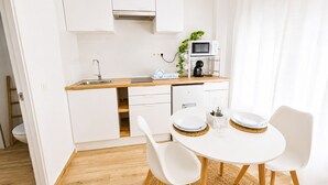 A modern kitchen with white cabinets, a wooden countertop, a sink, a microwave, and a coffee maker. - CREA Conil Apartments II (Conil de la Frontera)