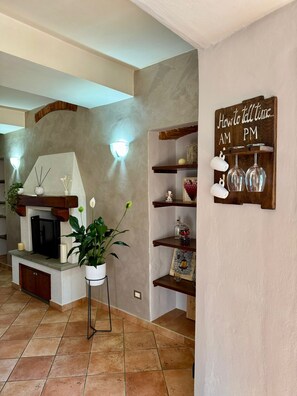 A living room with a fireplace, a wall-mounted sign, and shelves with decorative items.