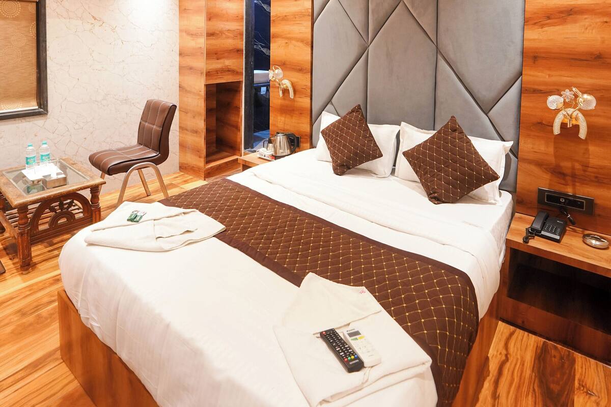Hotellihuone, jossa on sänky, tuoli, työpöytä, puhelin ja kattotuuletin.