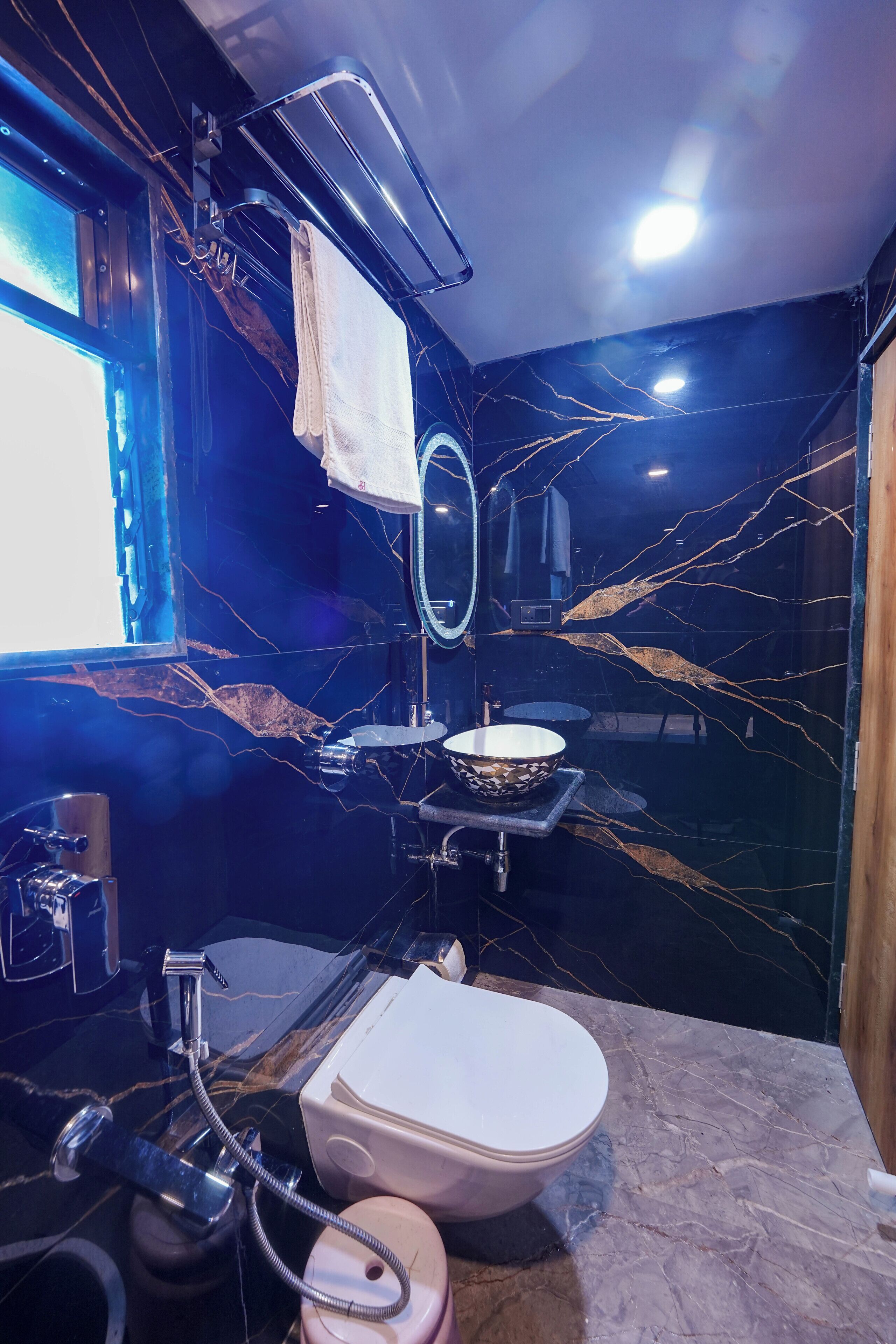 A bathroom with a marble sink, a toilet, a mirror, and a towel rack.