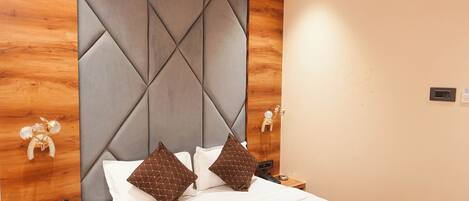 Una habitación de hotel moderna con una cama grande, cabecera de madera y ventilador de techo.