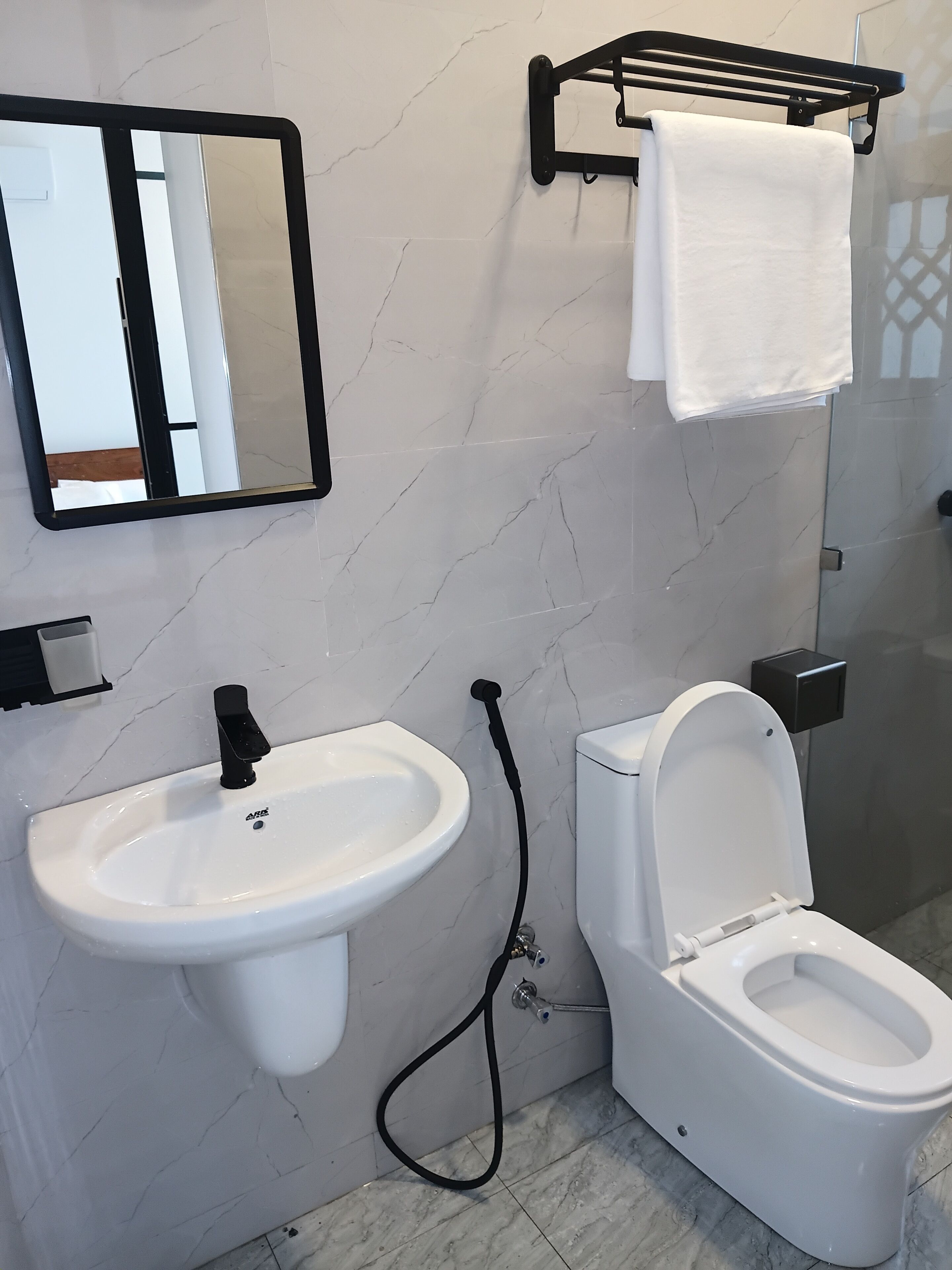Baño con lavamanos, inodoro y espejo blancos.