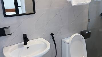 Baño con lavamanos, inodoro y espejo blancos.