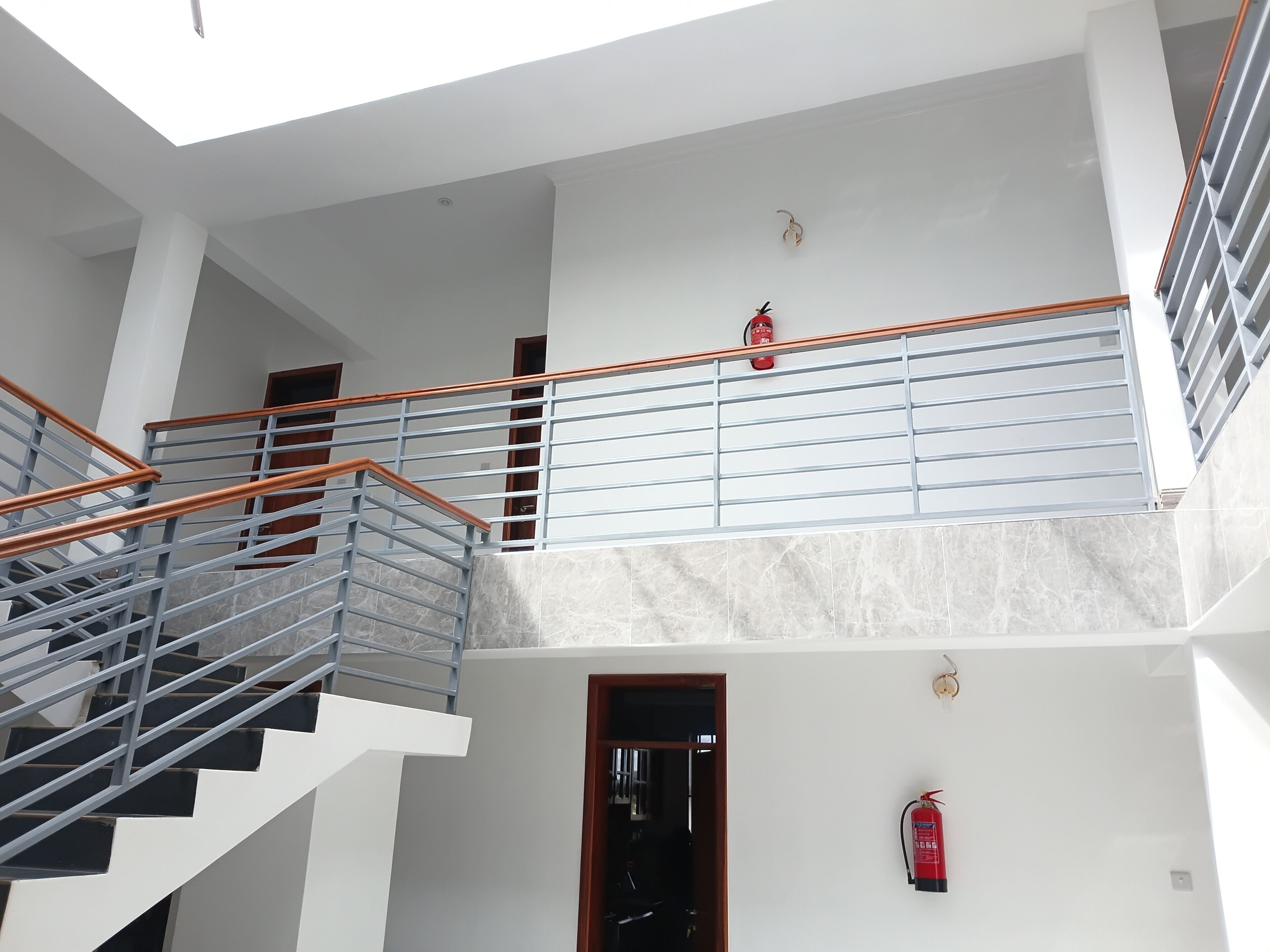 A multi-level interior with a staircase, metal railings, and a fire extinguisher.