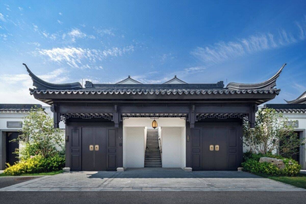 A traditional Chinese gate with a staircase leading to a dark entrance, surrounded by greenery.