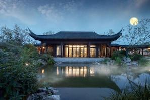 A traditional Chinese building with a pond in front, surrounded by greenery. - Canbeauty Golf Resort and SPA Weihai (Weihai)