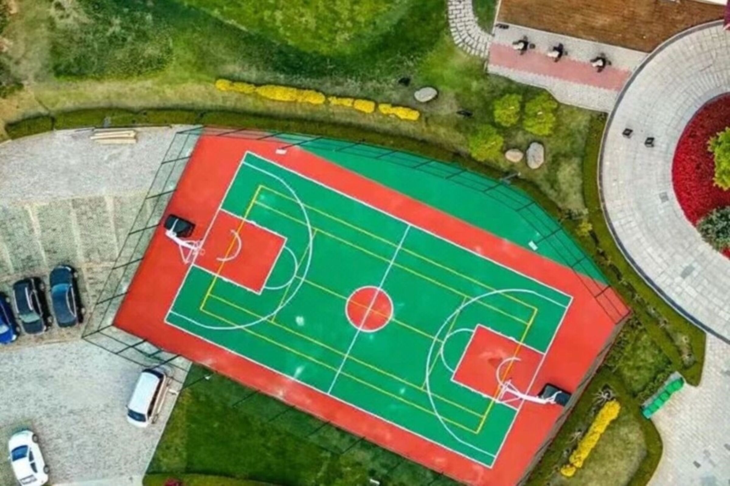 Vista aérea de una cancha deportiva con zonas verdes circundantes y una estructura de edificio circular.