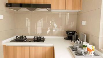 Una cocina moderna con estufa a gas, cafetera y una bandeja con tazas y una taza.