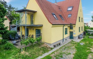 En gul bygning med rødt tag, balkon og trappe op til en øvre etage.