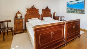 Ein Schlafzimmer mit einem hölzernen Bett, einem Nachttisch, einem Sessel und einem Bild an der Wand.